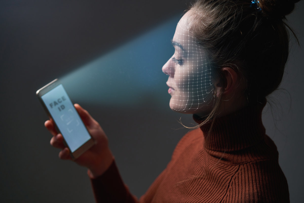 Female scans face using facial recognition system on mobile phon Reconocimiento facial con smartphone